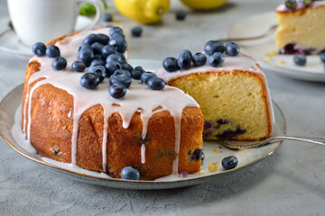Fruchtiger Zitronen-Heidelbeer-Kuchen mit süßer Glasur und frischen Beeren - Lemon blueberry cake covered with sweet sugar icing and bilberries, served with coffee