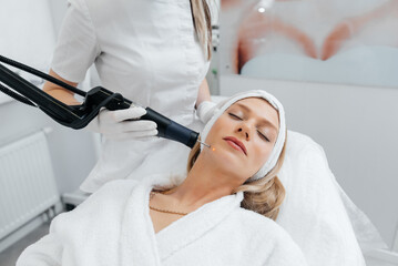 A young girl gets a charcoal peeling for the skin of the face in a beauty salon. Laser pulses cleanse the skin. Hardware cosmetology. The process of photothermolysis, warming the skin.