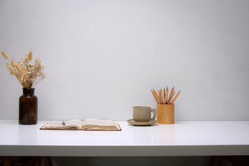 In front of a white desk with books placed.