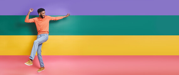 Fototapeta na wymiar Full length of playful African man dancing against colorful background