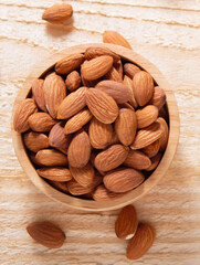 Almond kernels in wooden bowl on rustic dark wooden table.