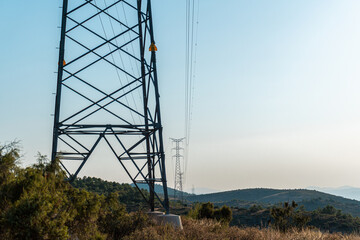 High voltage towers on hills in a summer sunset. 