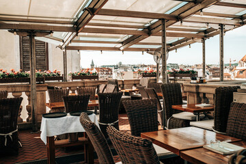 Beautiful terrace of restaurant in old european city on roof of building. View from high to downtown. Rattan furniture