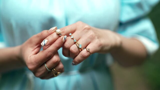 Beautiful gypsy woman wears exquisite jewelry on fingers - gold rings with natural stones, boho jewelry. Girl in blue dress. 