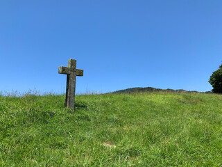 Stone cross on a hillside full of grass 