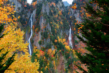 Autumn scenery of Ginga and Ryusei Waterfalls in Sounkyo Gorge, with beautiful fall colors on the rocky cliffs & majestic Kurodake mountain in background, in Daisetsuzan National Park, Hokkaido, Japan - obrazy, fototapety, plakaty