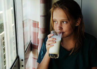 Portrait of a teenager girl at home with glass of milk - 517535314