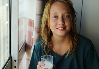 Portrait of a teenager girl at home with glass of milk - 517535320