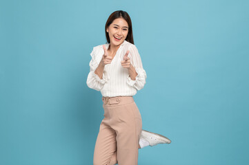 Young beautiful asian woman with smart casual cloth smiling with excitement pointing at camera isolated on blue background