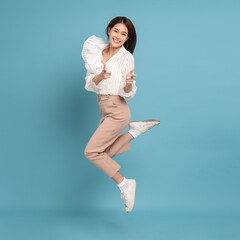 Young beautiful asian woman with smart casual cloth jumping and smiling with excitement pointing at...
