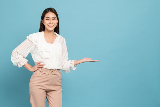 Young beautiful asian woman with smart casual cloth smiling and presenting copy space isolated on blue background