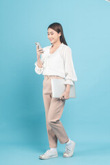Young beautiful asian woman with smart casual cloth use smartphone isolated on blue background