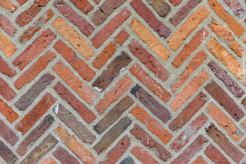 Bunte Klinkersteine oder Ziegel im Fischgrätenmuster angeordnet mit gruaen Fugen