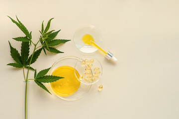 CBD oil in a pipette, capsules, THC tincture and cannabis leaves in a test tube on a beige...
