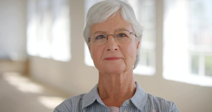 Portrait of a serious senior woman looking at the camera at home. Face of a content and wise old granny looking thoughtful while aging gracefully. Retired female with grey hair, wrinkles and glasses