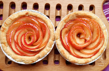 Pair of Fresh Baked Homemade Rose Shaped Apple Tartlets on Wooden Breadboard