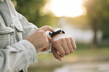 Man's hand touching a smartwatch. Close up shot of male's hand uses of wearable smart watch at...