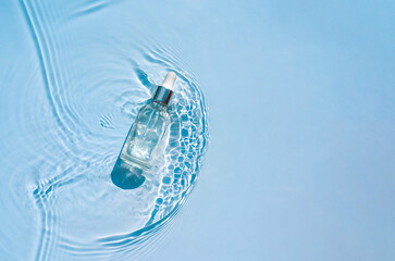 Moisturizing cosmetic product, serum in a transparent bottle with a dropper in water waves, blue...