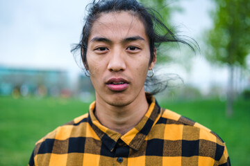 Portrait boy with asian features outdoors with plaid shirt