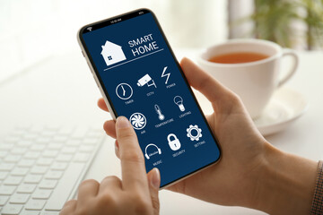 Woman using Smart Home app on mobile phone indoors, closeup