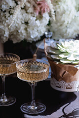 A bouquet of white hydrangeas and pink astilba, succulent, candles and a fashionable glass for dessert and champagne with wine inside. Cozy interior. The concept of a party, wedding and holiday.