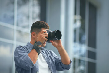 Fototapeta na wymiar Photographer taking picture with professional camera on city street