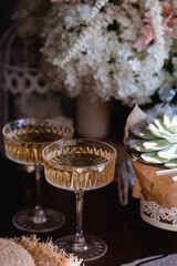 A bouquet of white hydrangeas and pink astilba, succulent, candles and a fashionable glass for dessert and champagne with wine inside. Cozy interior. The concept of a party, wedding and holiday.