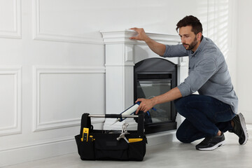 Man installing electric fireplace near white wall in room