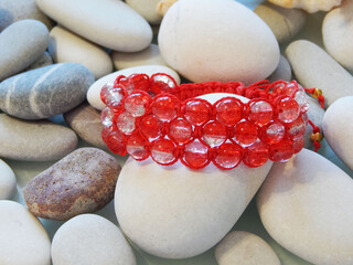 Red friendship bracelet on stones