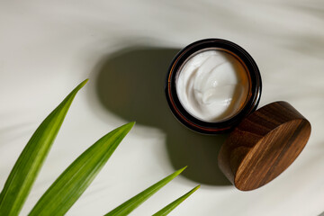 Fototapeta na wymiar Open jar of cosmetic cream on white table, top view