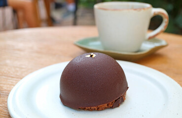 Closeup of Chocolate Mousse Dome Cakes with Blurry Cup of Coffee in the Backdrop