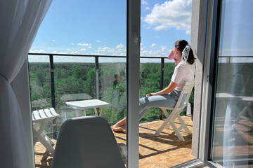 a girl with a mug on the balcony drinks morning tea and takes a break from the hustle and bustle of...