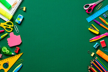Frame of colorful school supplies on green table. Back to school concept. Top view. Flat lay. - obrazy, fototapety, plakaty