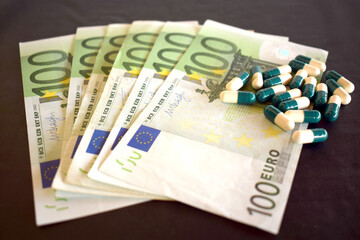 100 Euro Cash banknotes with pills on a black background