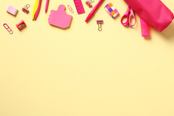 Frame of pink school supplies on yellow table. Flat lay, top view, copy space. Back to school concept.