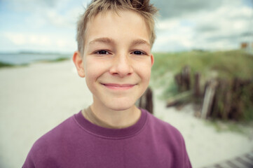 Portrait of handsome teenage boy on beach with white sand at summer day