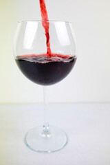 Vertical shot. A glass of red wine on a light background.