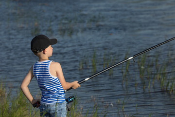 Little boy is fishing at sunset on the lake