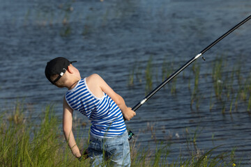 Little boy is fishing at sunset on the lake