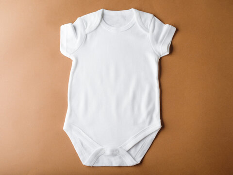 White bodysuit made of cotton fabric on a brown background. Clothing for boys and girls, newborns. Flat layout for the design and placement of advertising, logos, prints.