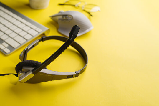 Modern devices for office, home office. Laptop, headphones, computer mouse on a bright yellow background. Advertising, banner. There are no people in the photo.