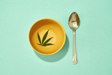Top view of green marijuana leaf in bowl and spoon