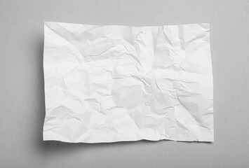 Obraz premium Sheet of white crumpled paper on grey background, top view