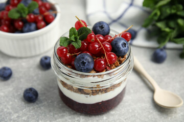 Delicious yogurt parfait with fresh berries and mint on light grey table, closeup