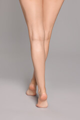 Woman with beautiful long legs on grey background, closeup