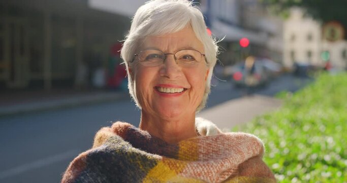A stylish senior woman that enjoys fashion standing outside in a city. Portrait of an edgy old female with a bright smile on a sunny day. A happy and youthful retired pensioner with a vibrant style