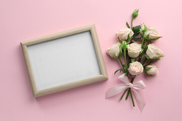 Beautiful bouquet of roses with blank white board on light pink background, flat lay. Space for text