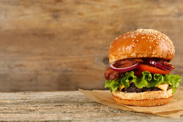 Tasty burger on wooden table, space for text. Fast food