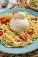 Plate of delicious pasta with burrata and tomatoes on table, closeup
