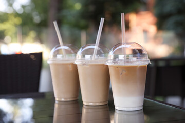 Plastic takeaway cups of delicious iced coffee on table in outdoor cafe